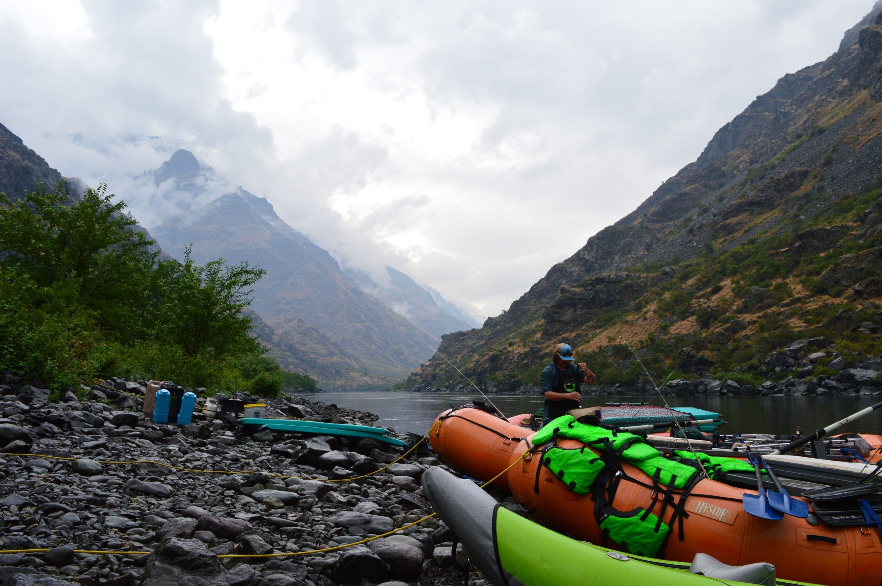 Whitewater rafting boat in the foreground with misty river canyon in the background.