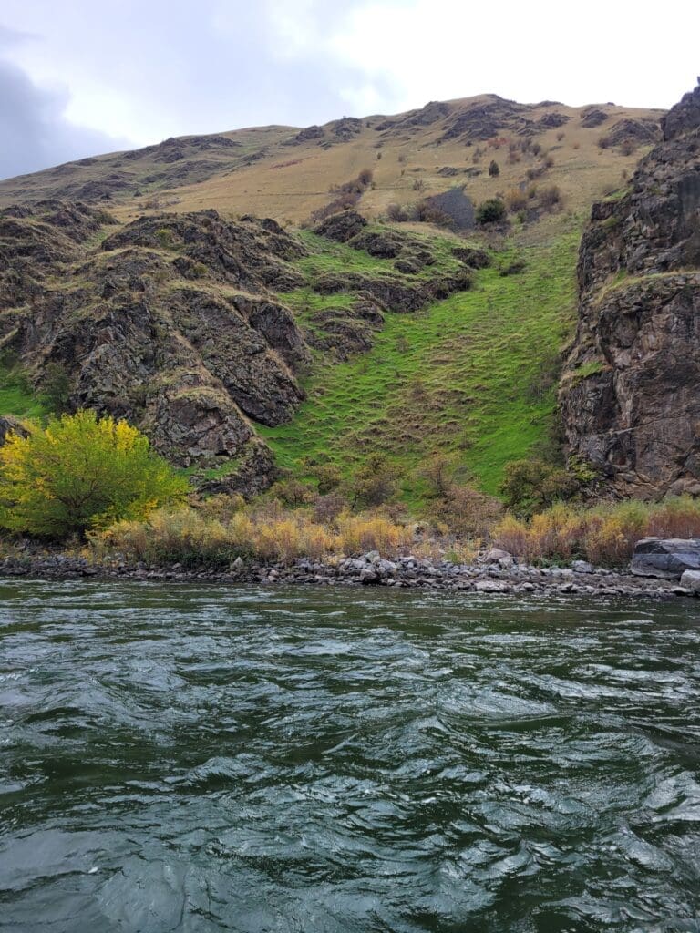 River in foreground with mountainous green and rocky wall landscape